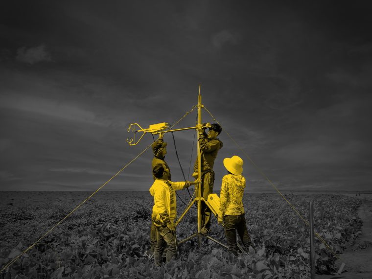 A field team installing a micrometeorological tower in a crop field.