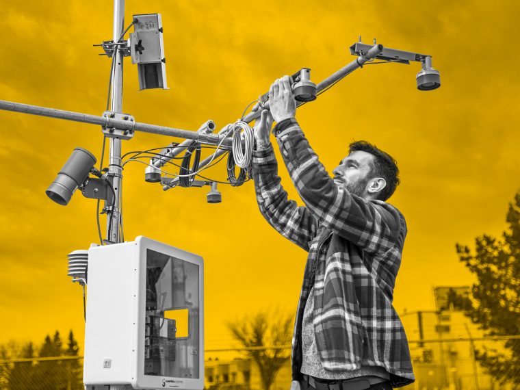 A technician servicing sensors mounted on a weather station mast.